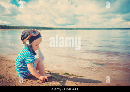 boy playing with a paper plane in aviator hat Stock Photo