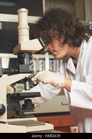young man working in lab with microscope Stock Photo