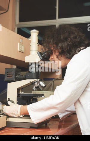 young student scientist analyzing a sample in microscope Stock Photo