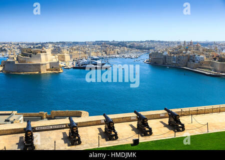 View of the cannons of upper barraka gardens, valetta, malta with the grand harbour and birgu, sanglea and Fort Saint Angelo in the background Stock Photo