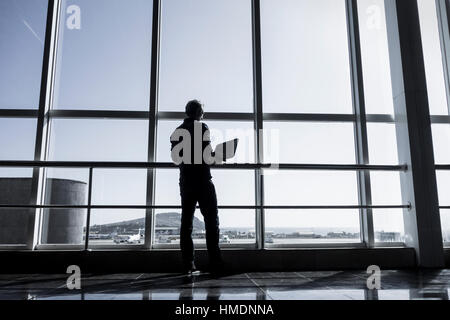 Man using laptop in airport terminal building Stock Photo