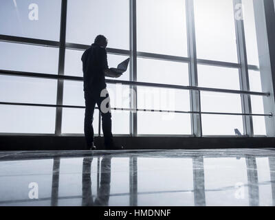 Man using laptop in airport terminal building Stock Photo