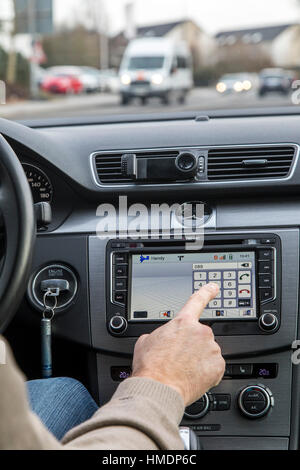 A car driver is using the cars navigation system,  while driving the car, Stock Photo