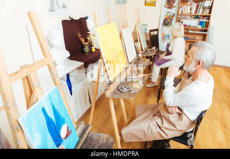 Elderly artist sitting in painting class Stock Photo