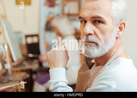 Elderly artist posing in painting class Stock Photo