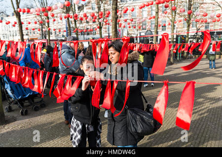 ROTTERDAM,HOLLAND - JANUARY 28 2016: Unidentified woman and girl making wishes on chinese new year by hanging red ribbon on a line in Rotterdam on on Stock Photo