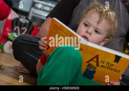 Denver, Colorado - Adam Hjermstad Jr., 2 1/2, reads a book, A is for Activist, that he was given for Christmas. Stock Photo