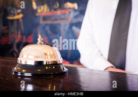 Hotel reception service bell with concierge welcoming in the background Stock Photo