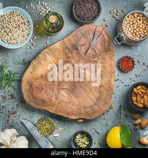 Ingredients for healthy cooking. Beans, rice, chickpeas, almond, seeds, herb, spices and olive oil over grey concrete textured background, wooden boar Stock Photo