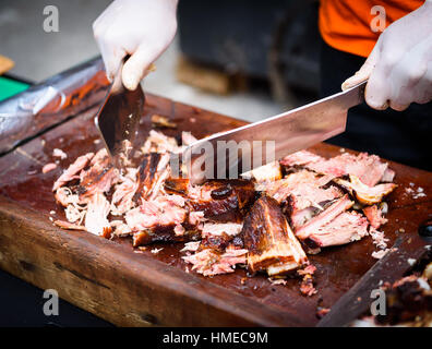 Chef Hands cutting Grilled spare beef or pork back ribs prepared in smoker with a hatchet. Delicious roasted cuts of meet made on barbecue smoker on a Stock Photo