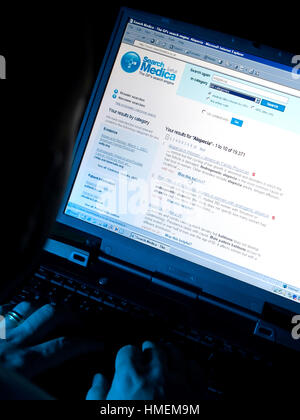 Dark and moody photograph of medical search engine being used by NHS reception or medical emplyee Stock Photo