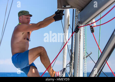 Man tightens the ropes on his sailing yacht. Stock Photo