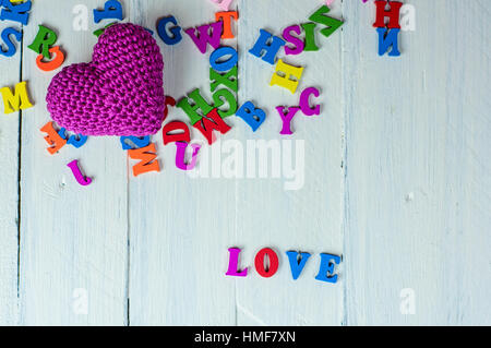 White wooden background with colorful letters and a little red knitted heart Stock Photo