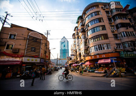 Man on bicycle crosses a junction in the back streets of Shanghai, China Stock Photo