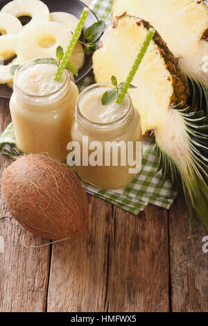 Delicious drink made from pineapple and coconut milk in a glass jar closeup on the table. vertical Stock Photo