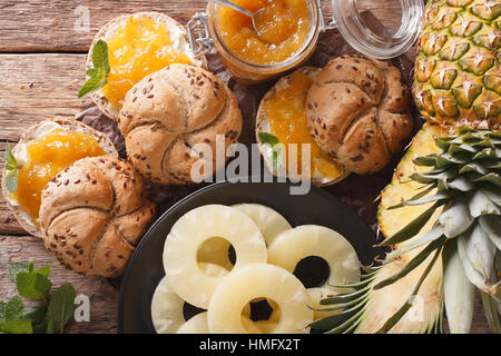 pineapple jam in a glass jar and sweet sandwiches close-up on the table. Horizontal view from above Stock Photo