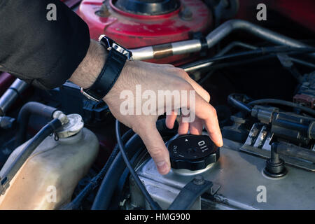 Man is opening the oil cap from a car engine. Stock Photo