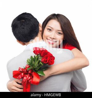 romantic moment: young man giving a rose to his girlfriend. Embracing couple hugging happy. Smiling interracial couple in love isolated on white backg Stock Photo