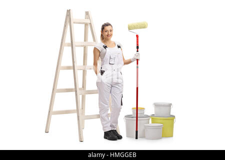 Full length portrait of a female decorator with a paint roller standing in front of a ladder isolated on white background Stock Photo
