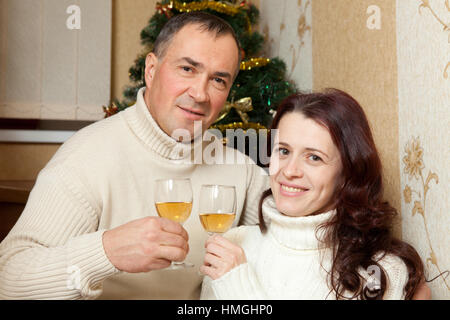 Christmas Couple.Happy Smiling Family at home celebrating.New Year People. Middle-aged couple near a Christmas tree with glass of champagne in interior of house Stock Photo