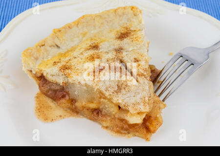 A slice of homemade apple pie on a white plate, blue place mat. USA. Stock Photo