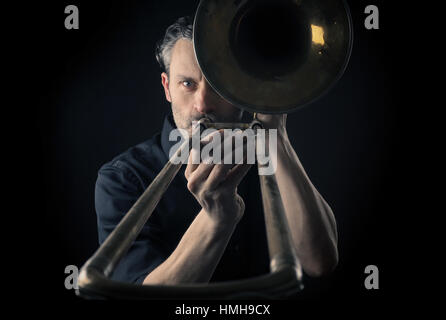 Portrait of a musician with an old dusty trombone on a dark background Stock Photo