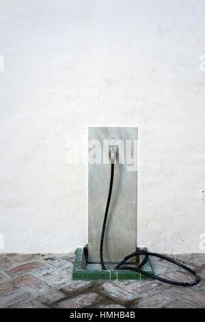 Out door tap with black hose pipe attached against a white wall and marble tile Stock Photo