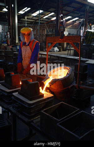 Foundrymen pour molten iron into moulds for making fire grates Stock Photo