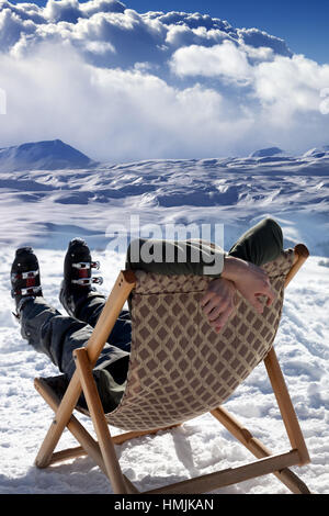 Skier at winter mountains resting on sun-lounger. Caucasus Mountains, Georgia, region Gudauri. Stock Photo