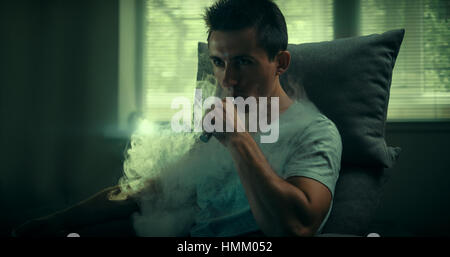 Stylish vaper. Young guy. Man using an advanced personal vaporizer or e-cigarette. Stock Photo