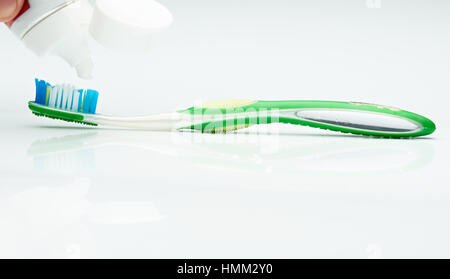 macro of putting white tooth paste on green brush isolated Stock Photo