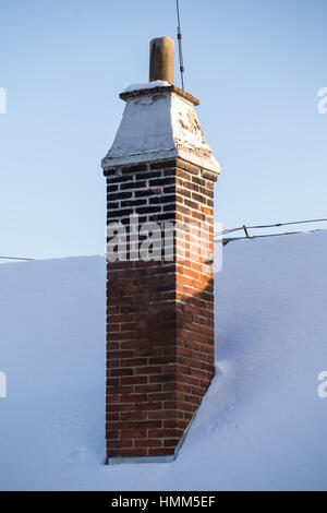 Old brick chimney and roof covered with snow Stock Photo