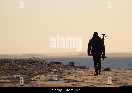 Silhouette of a photographer walking on the beach at Spurn Point, East Yorkshire, UK Stock Photo