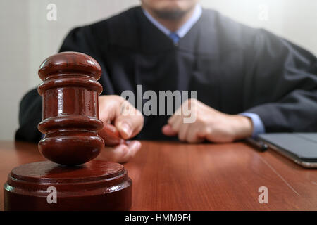 justice and law concept.Male judge in a courtroom striking the gavel,working with digital tablet computer docking keyboard on wood table Stock Photo