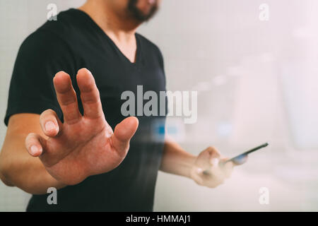 Designer hand pressing an imaginary button,holding smart phone,digital screen graphic virtual icons,graph,diagram,filter effect Stock Photo