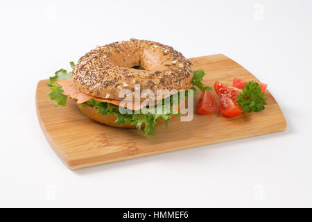 bagel sandwich with smoked salmon on wooden cutting board Stock Photo