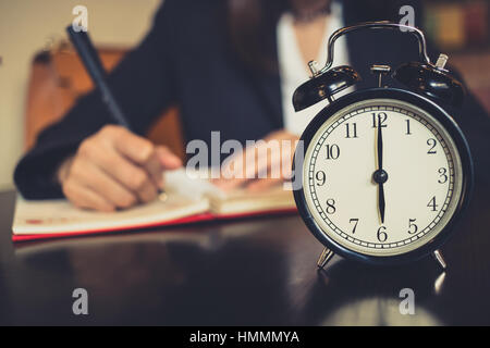 Time working, clock times at 6 o'clock with blur women business work writing or writer. Stock Photo