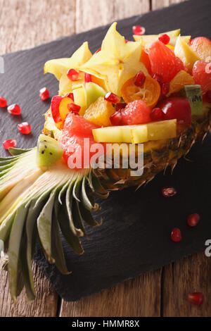 Salad of tropical fruit on a plate of pineapple close-up on the table. vertical Stock Photo