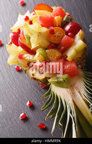 Ripe pineapple stuffed with fresh tropical fruits close-up on the table. vertical Stock Photo