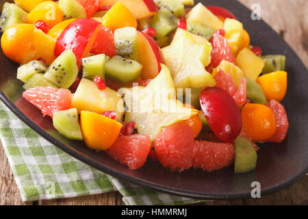 Exotic fruit salad with orange, kumquat, pineapple, carambola, grapefruit, plums and kiwi fruit close-up on a plate. horizontal Stock Photo