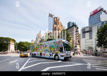 New York City - June 22: Painted bus at Columbus Circle in New York with blue sky and the new One57 tower in the background. Taken with a shift lens o Stock Photo