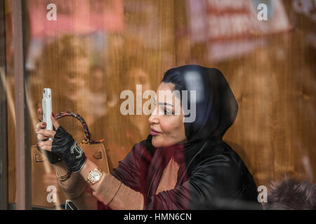 London, UK. 4th February, 2017. A muslim woman in a smart, Park Lane, hotel films the march as it goes past - A march against racism and to ban the ban (against immigration from certain countries to the USA) is organised by Stand Up To Racism and supported by Stop the War and several unions. It stated with a rally at the US Embassy in grosvenor Square and ended up in Whitehall outside Downing Street. Thousands of people of all races and ages attended. Credit: Guy Bell/Alamy Live News Stock Photo