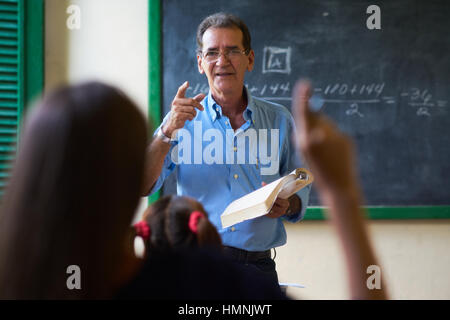Young people and education. Group of hispanic students in class at school during lesson. Girl raising hand and asking question to teacher Stock Photo