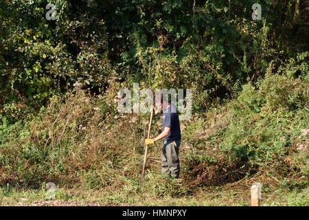 Wroxham Norfolk  , United Kingdom - October 25, 2016: Man undertaking conservation work alongside River Yare Stock Photo