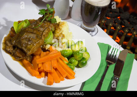 A pub/restaurant dish of Braised Beef Steak served with creamed potato, sprouts and carrots and a glass of beer/ale. Stock Photo