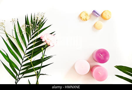 Beauty blogger flat lay on white.  Green leaves and carnation flower, pink ombre candles, macaroons. Woman decorating ideas. Negative space for text Stock Photo