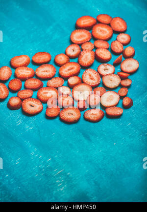 Heart of fresh strawberries over bright blue painted background Stock Photo