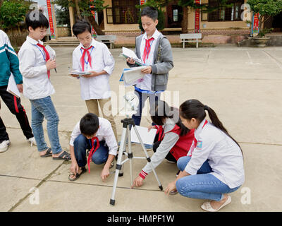 School children attending outdoor classroom, learning how to operate a sextant, Thai Giang Pho Boarding School. Stock Photo