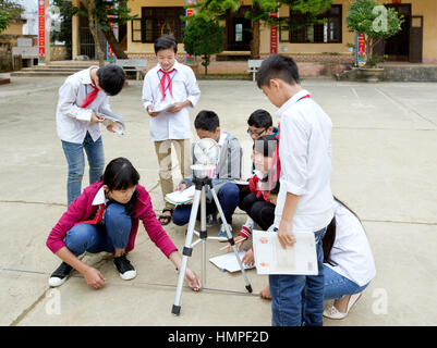 School children attending outdoor classroom, learning how to operate a sextant, Thai Giang Pho Bording School. Stock Photo