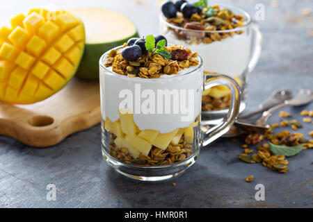 Mango yogurt parfait with granola on top in glass mugs Stock Photo